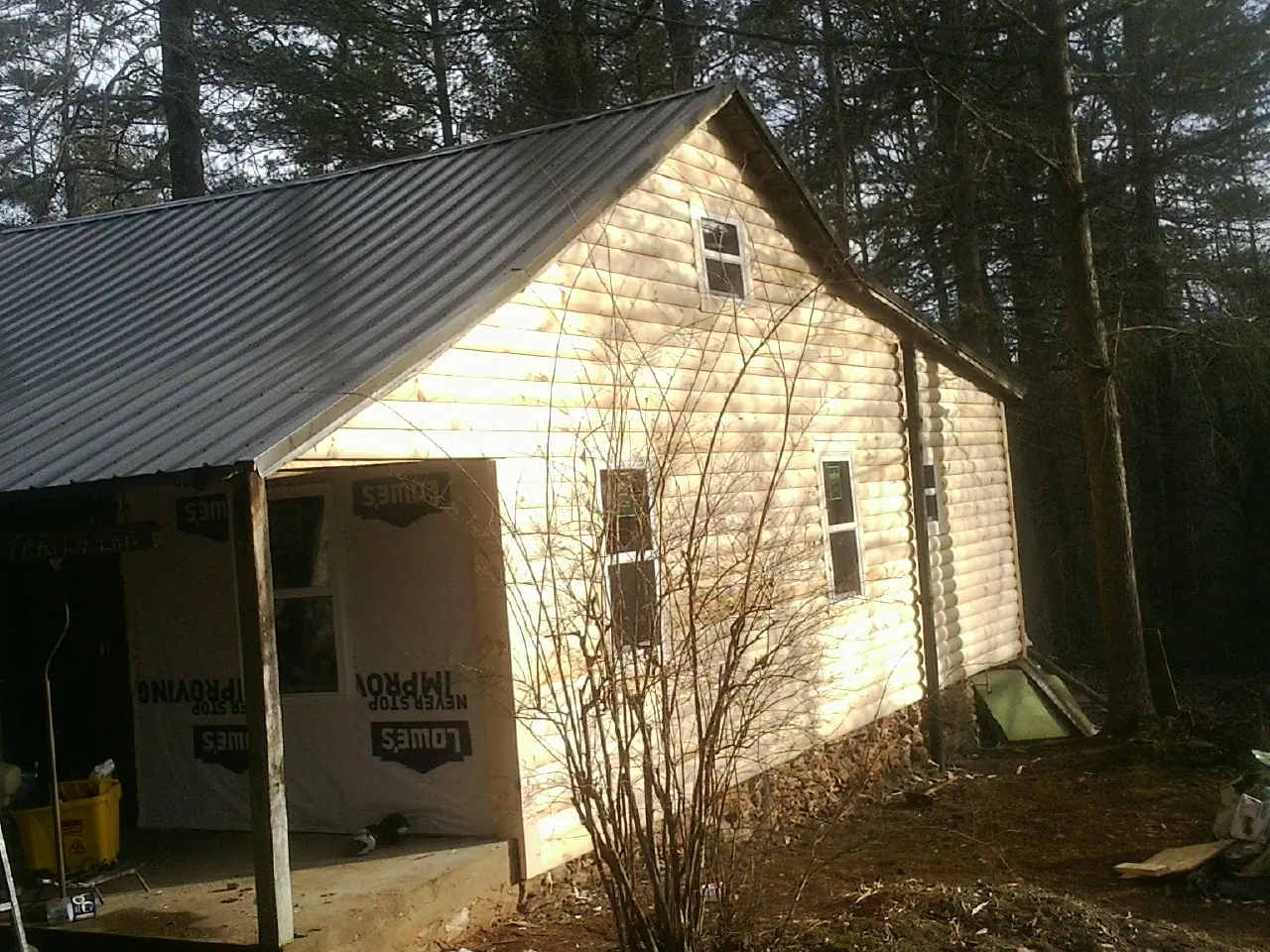 Log siding gable end under a dark metal roof edge in Rhodes