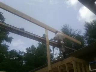 Carpenter setting a ridge beam over a new addition frame — Ice Dam Removal by Roofing Brothers in Rhodes