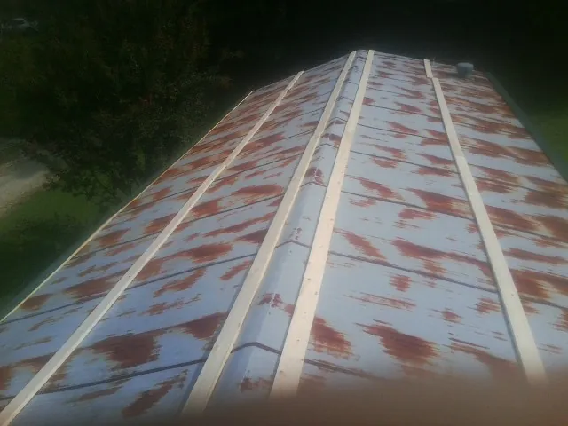 Rusted metal roof panels with new wood purlins before replacement — Storm Damage Roof Repair in Rhodes by Roofing Brothers