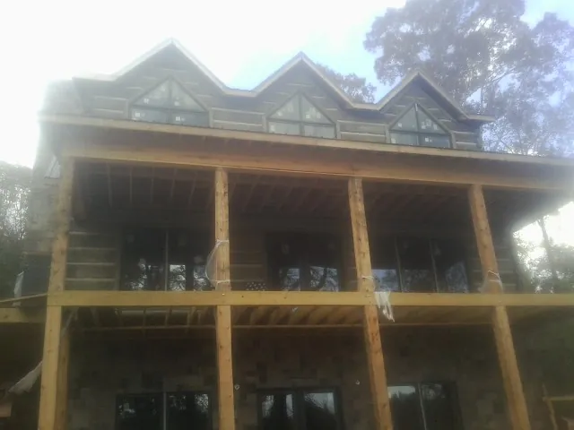 Dormers and porch framing on a large log home under construction — Roof Coating work by our crew in Rhodes