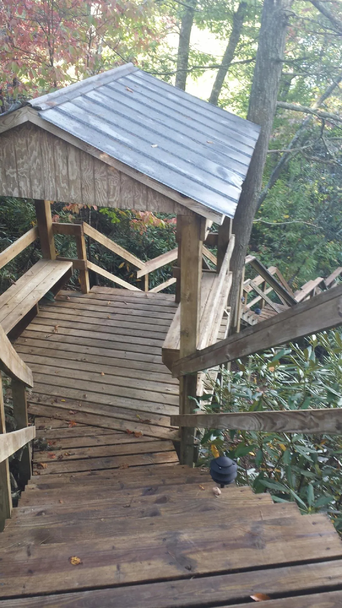 Metal roofed shelter over wooden steps on a wooded walkway — Skylight Repair & Installation work by our crew in Rhodes