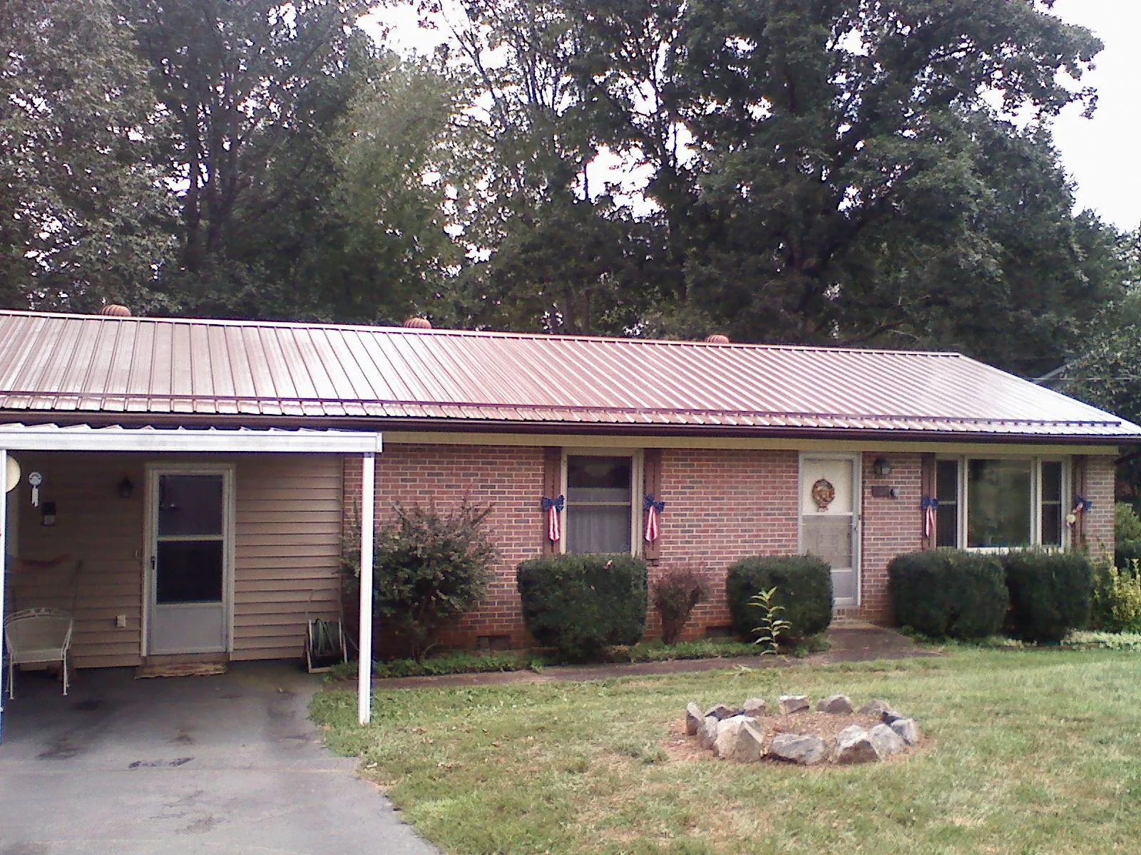 Bronze metal roof and carport on a brick ranch home — Roof Repair work by our crew in Rhodes