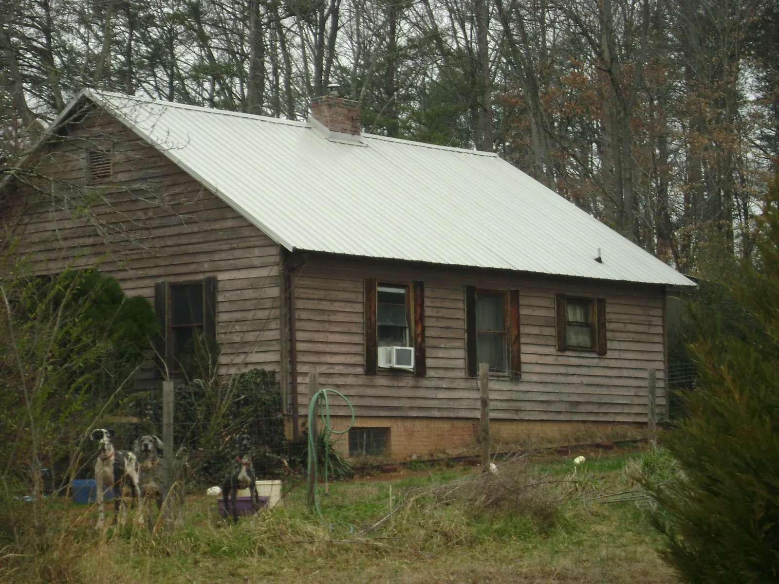 White metal roof on an old wood sided farmhouse, from a Asphalt Shingle Roof Repair job in Rhodes