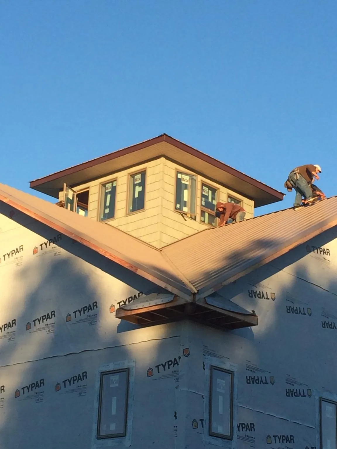 Roofers working around a rooftop cupola on a new metal roof at sunset — Roof Waterproofing in Rhodes by Roofing Brothers